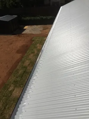 Dark corrugated roof rib-fixed gutter guard install